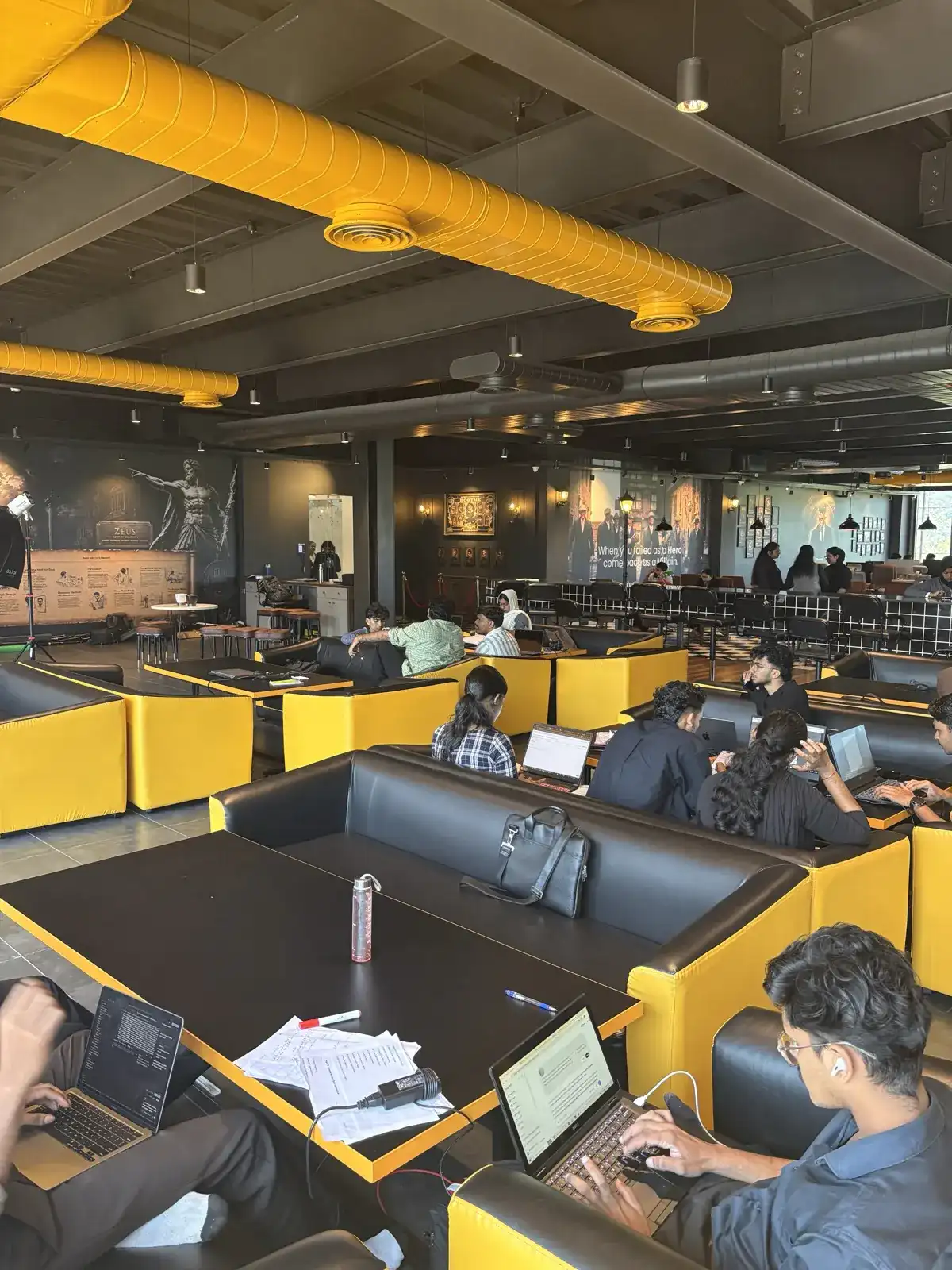 Yellow booth seating on the Rootmedia floor with students working on laptops