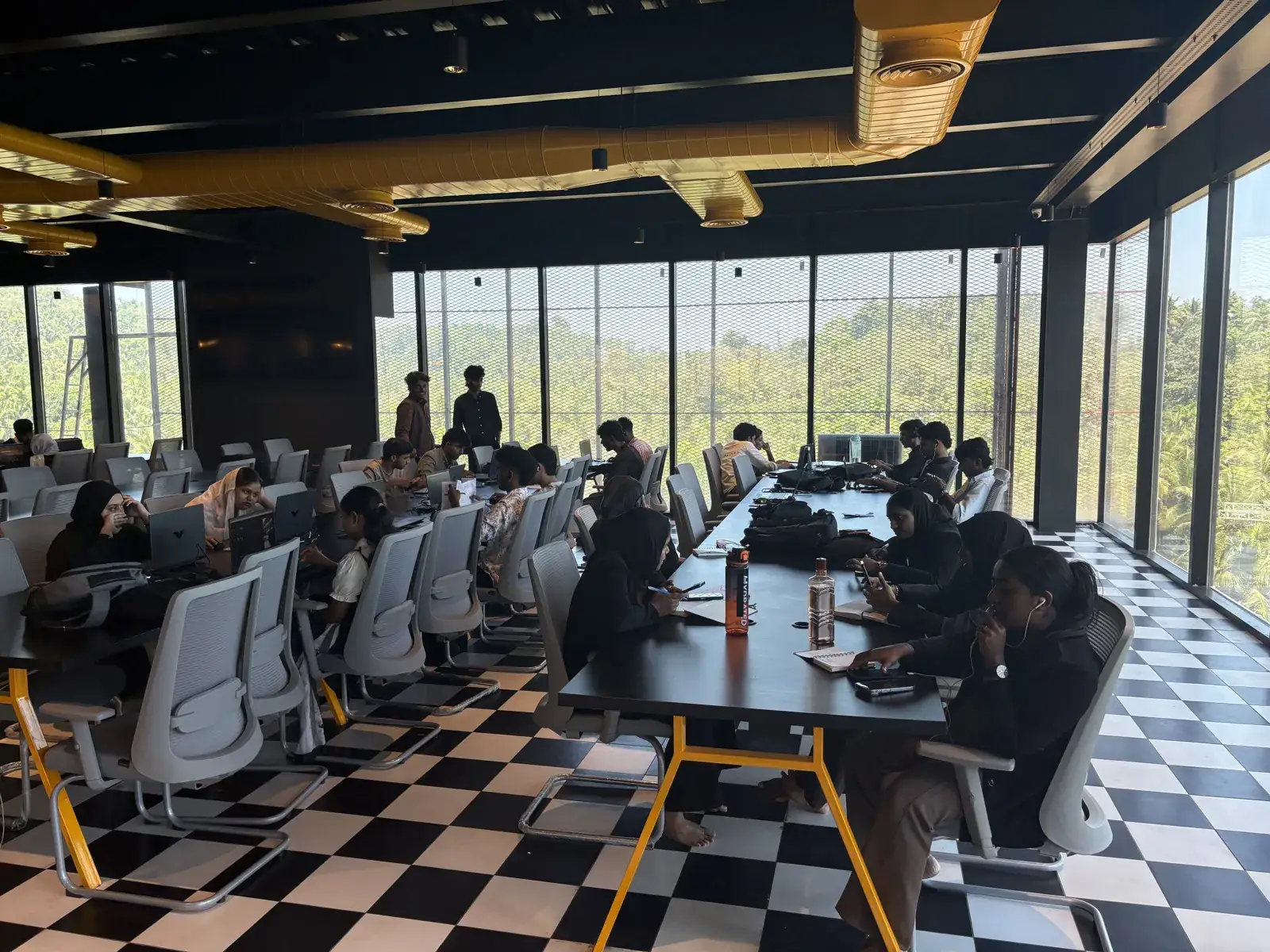 A session running at the long table beside the floor-to-ceiling windows, treeline visible outside