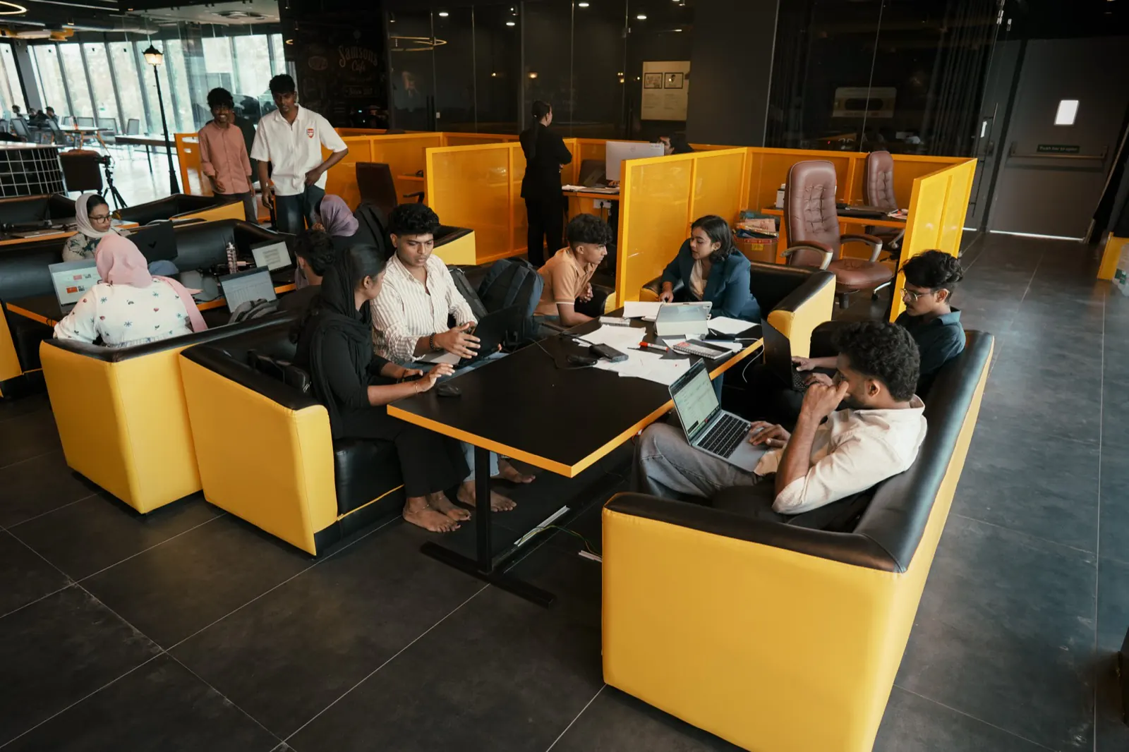 Students spread across the yellow collaboration booths, seen from the walkway above