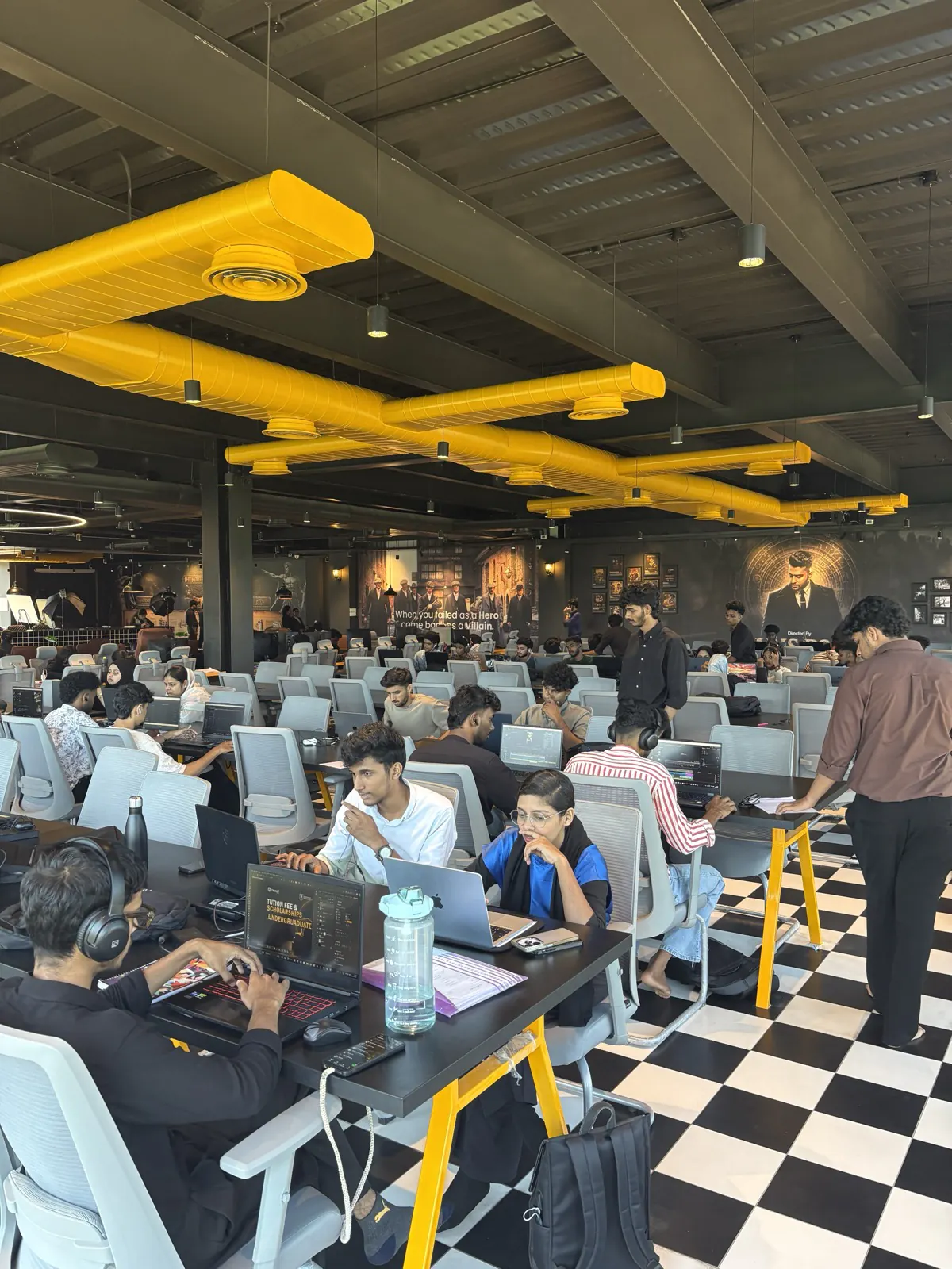 The Rootmedia training floor in Kozhikode — rows of workstations under yellow ductwork, students working at monitors