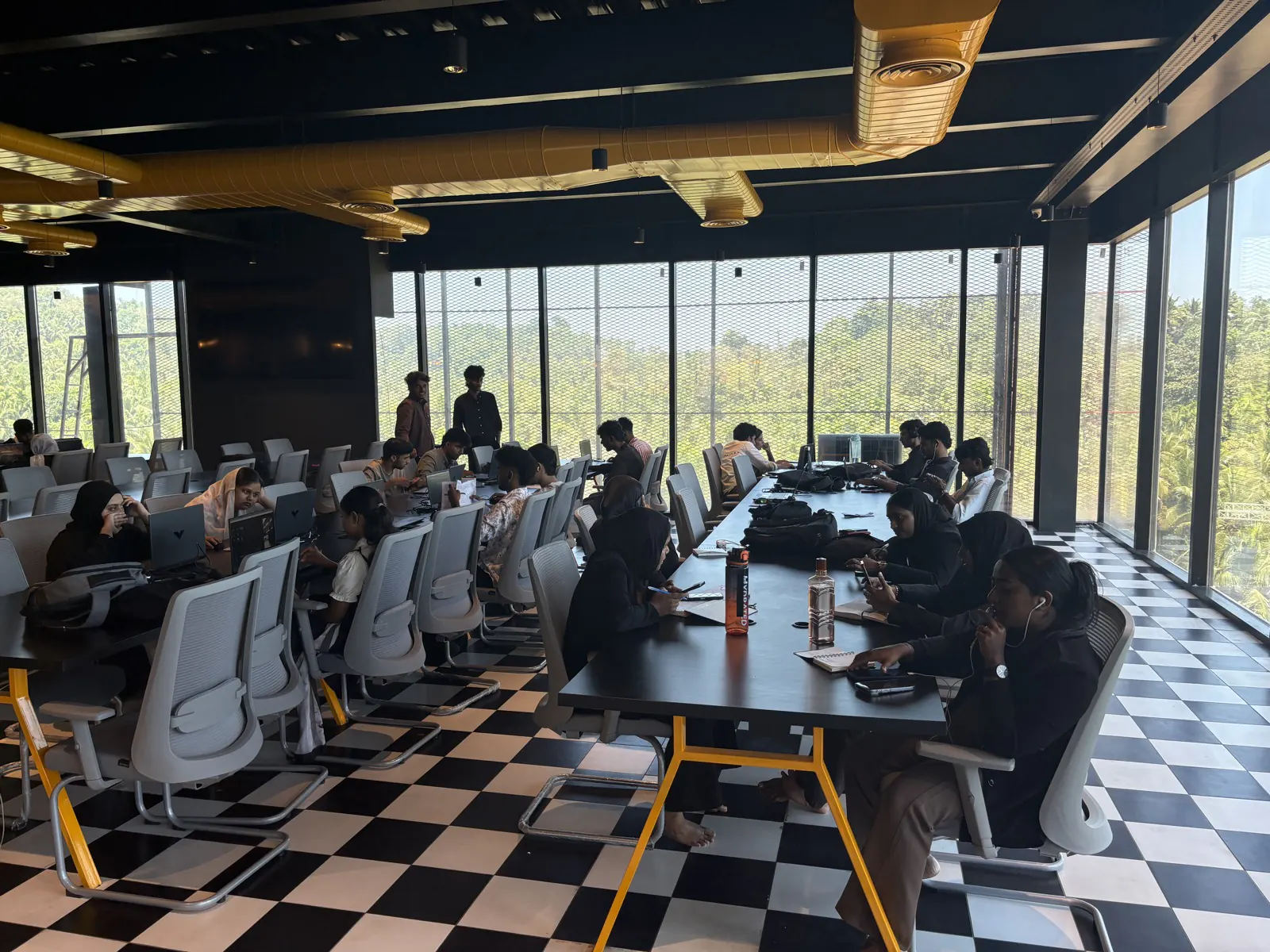 A session running at the long table beside the floor-to-ceiling windows, treeline visible outside