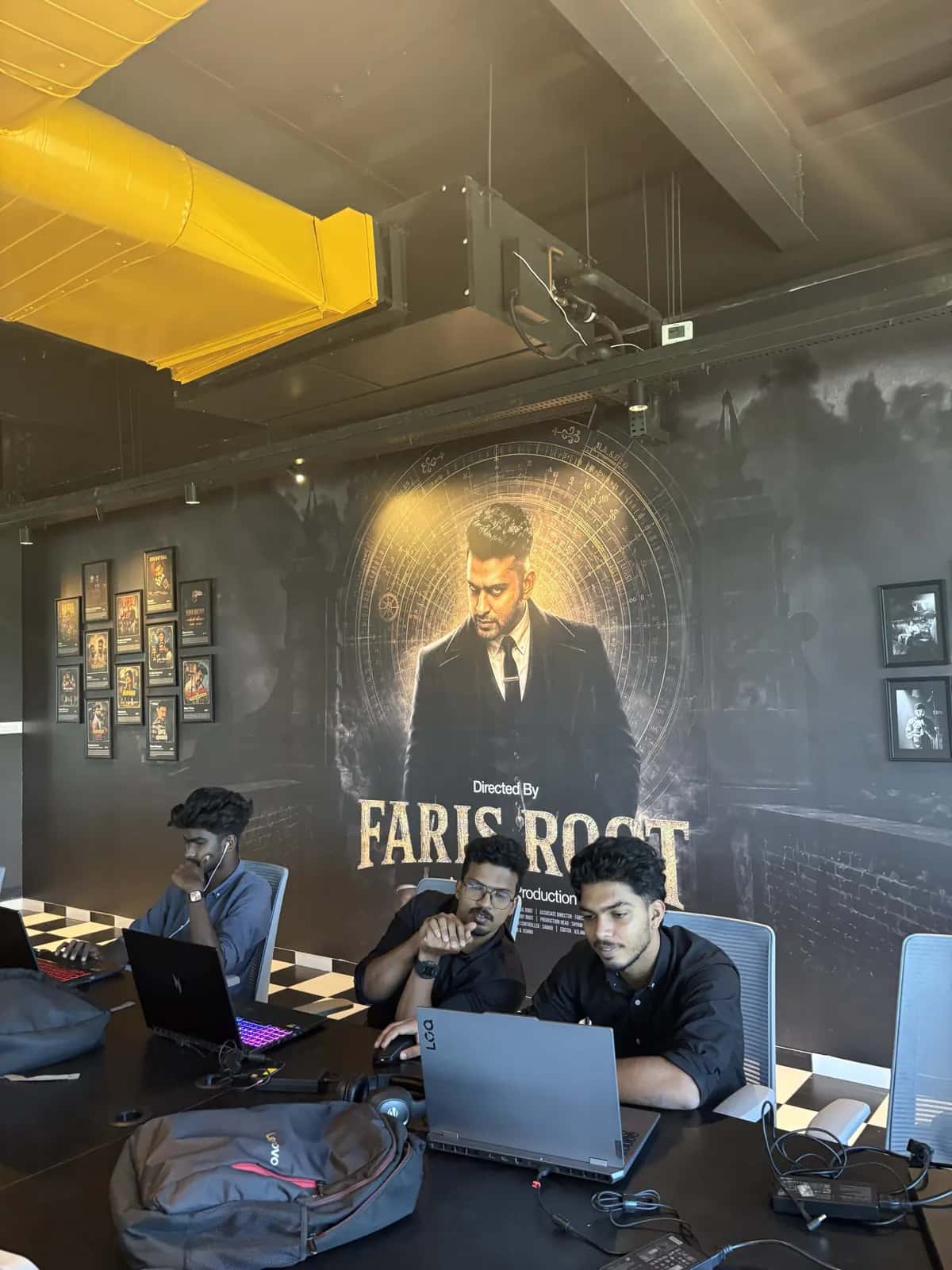 Students working at laptops in front of the Faris Root production mural